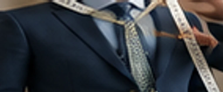A tailored dark suit jacket being fitted on a mannequin